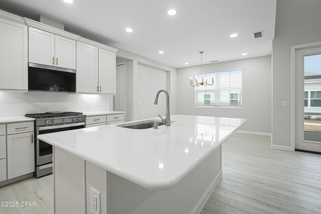 kitchen featuring recessed lighting, light countertops, visible vents, stainless steel appliances, and a sink
