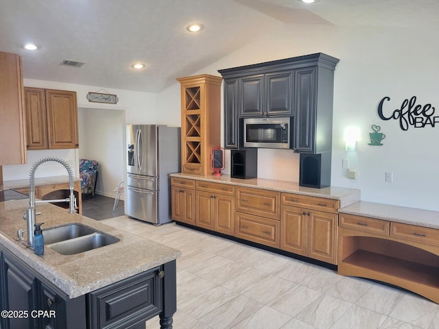 kitchen with vaulted ceiling, light stone counters, visible vents, stainless steel appliances, and a sink