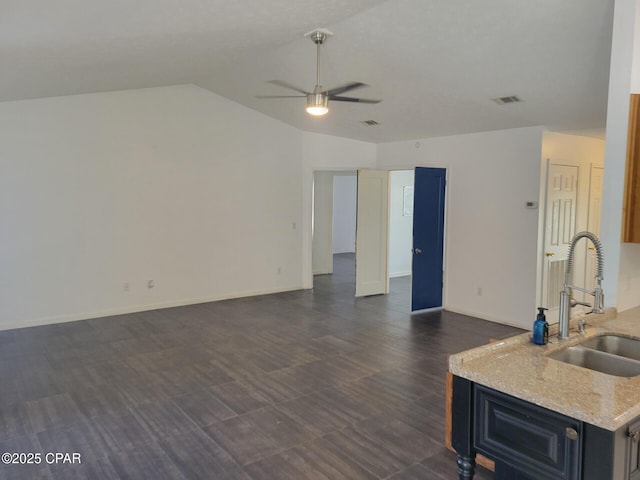 interior space with baseboards, a sink, open floor plan, ceiling fan, and lofted ceiling