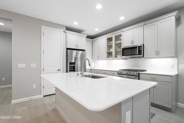 kitchen featuring light wood-type flooring, stainless steel appliances, baseboards, and a sink