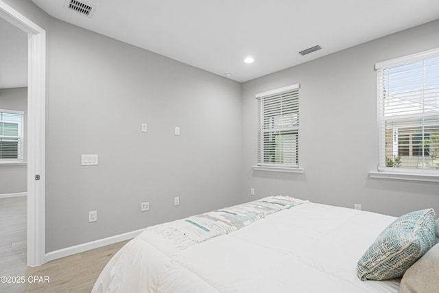 bedroom featuring light wood-style floors, visible vents, baseboards, and multiple windows