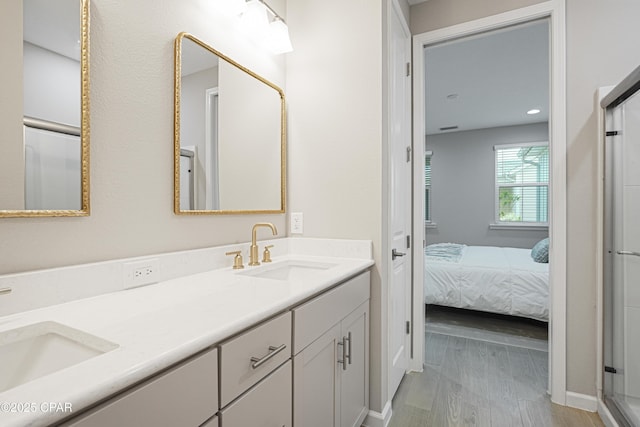 ensuite bathroom featuring connected bathroom, baseboards, a sink, and double vanity