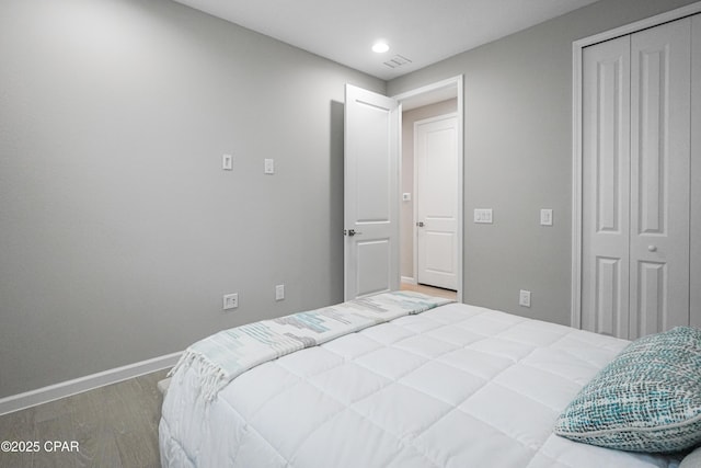 bedroom with baseboards, wood finished floors, recessed lighting, and a closet