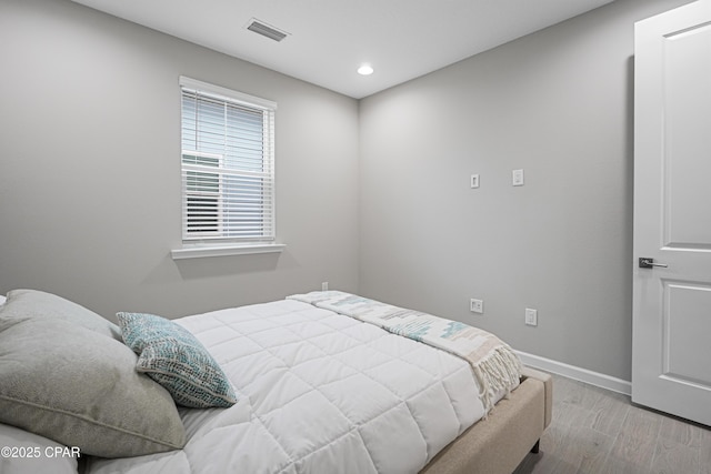 bedroom with baseboards, wood finished floors, visible vents, and recessed lighting
