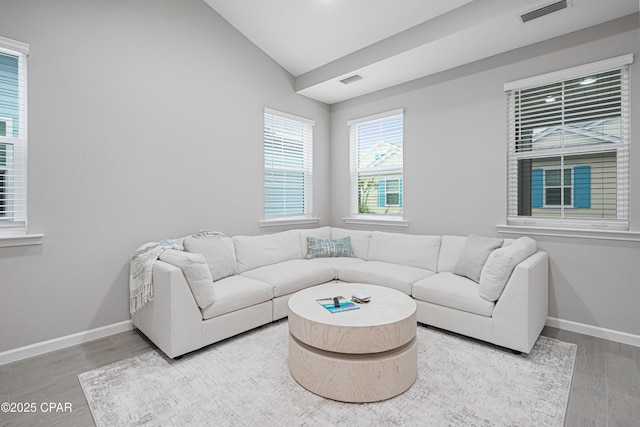 living area with vaulted ceiling, baseboards, wood finished floors, and visible vents