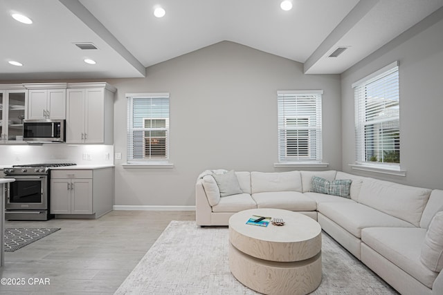 living area featuring light wood finished floors, recessed lighting, lofted ceiling, and a healthy amount of sunlight
