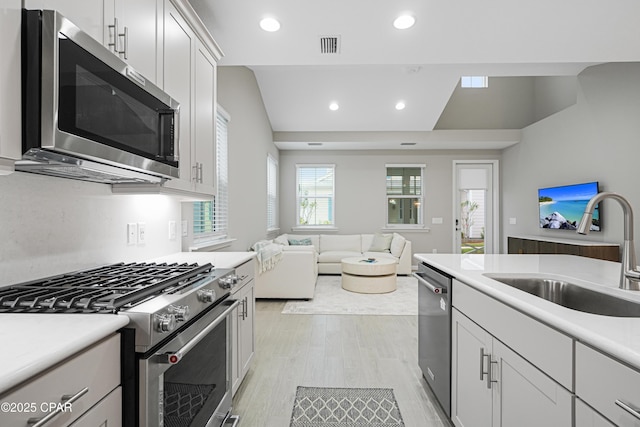 kitchen with stainless steel appliances, light wood-style flooring, a sink, open floor plan, and visible vents