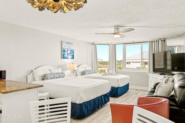 bedroom with light wood-style floors, baseboards, a ceiling fan, and a textured ceiling