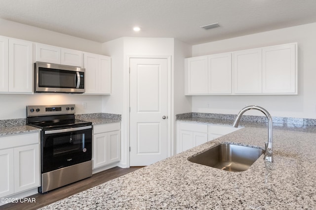 8028 Greyling Cir, Youngstown, FL 32466 - kitchen featuring stainless steel appliances, dark wood-style floors, a sink, white cabinets, and recessed lighting
