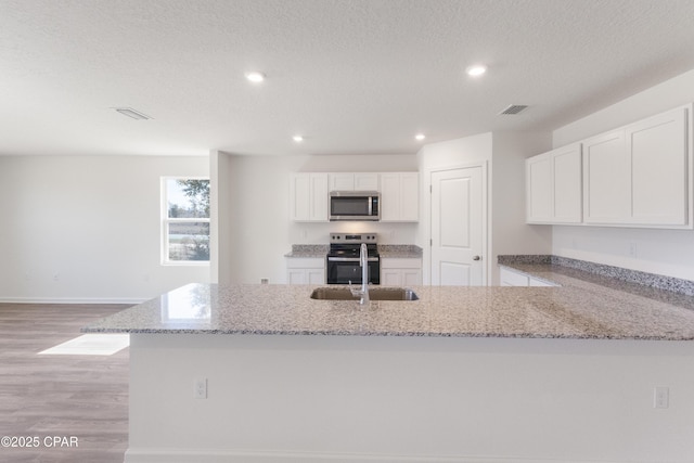 8028 Greyling Cir, Youngstown, FL 32466 - kitchen with appliances with stainless steel finishes, light wood-type flooring, white cabinets, light stone countertops, and recessed lighting
