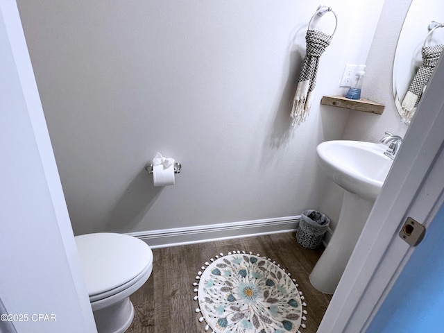 bathroom featuring baseboards, wood finished floors, and toilet