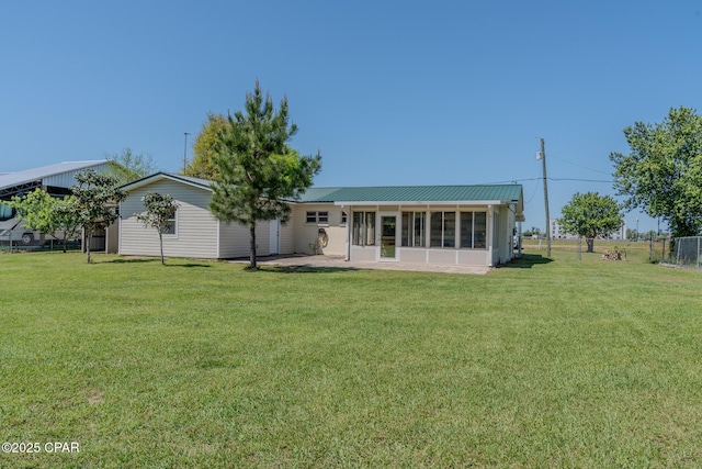 rear view of property with a sunroom, a patio, metal roof, and a lawn