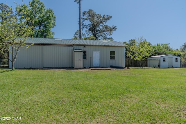exterior space with an outdoor structure, an outbuilding, metal roof, fence, and a lawn