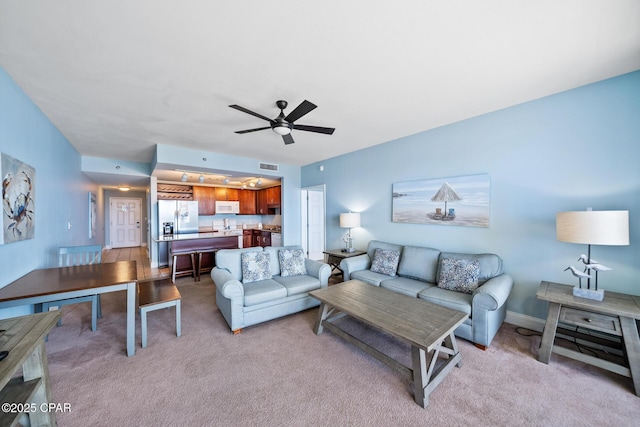 living area featuring light carpet and ceiling fan