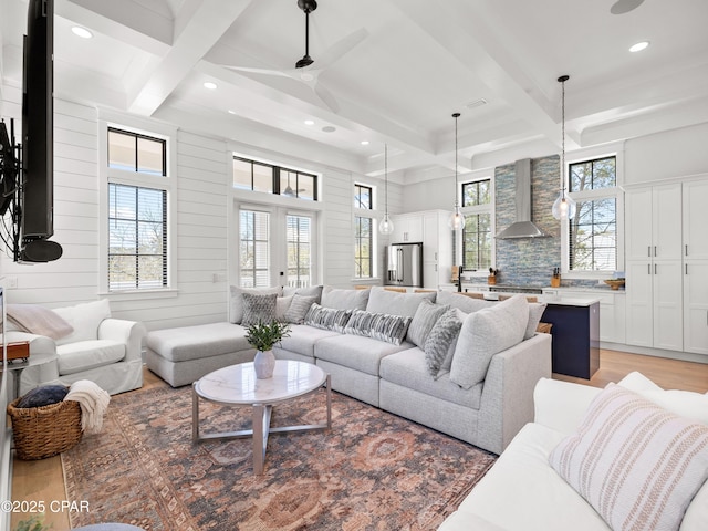 living area with beam ceiling, coffered ceiling, and light wood-style floors