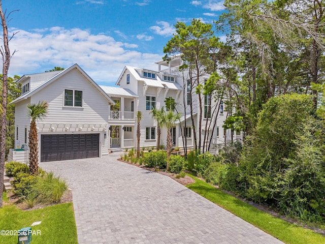view of front facade with a balcony, decorative driveway, an attached garage, a standing seam roof, and metal roof