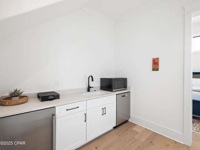 bar with light wood-style floors, black microwave, refrigerator, dishwasher, and a sink