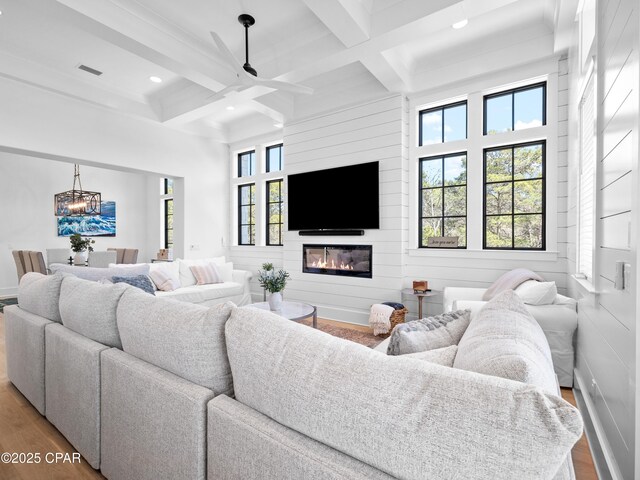 living area with visible vents, wood finished floors, beam ceiling, and coffered ceiling