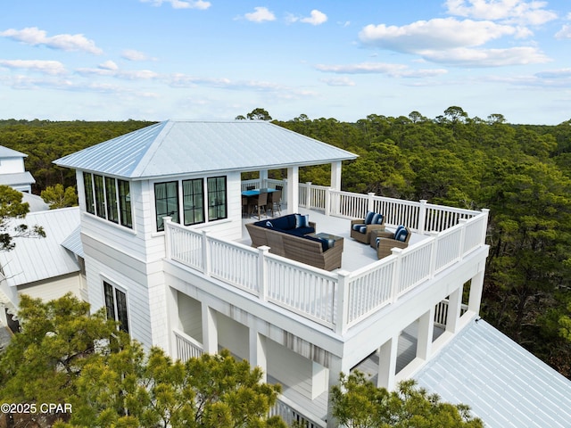 back of house with outdoor lounge area, a forest view, and metal roof