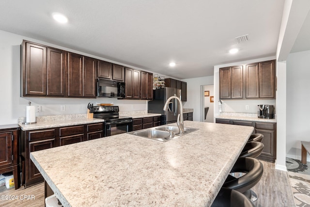 3946 Whitehead Blvd, Panama City, FL 32404 - kitchen featuring a breakfast bar, visible vents, a sink, dark brown cabinetry, and black appliances