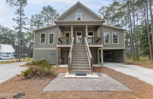 beach home featuring stairway, driveway, a carport, board and batten siding, and a porch