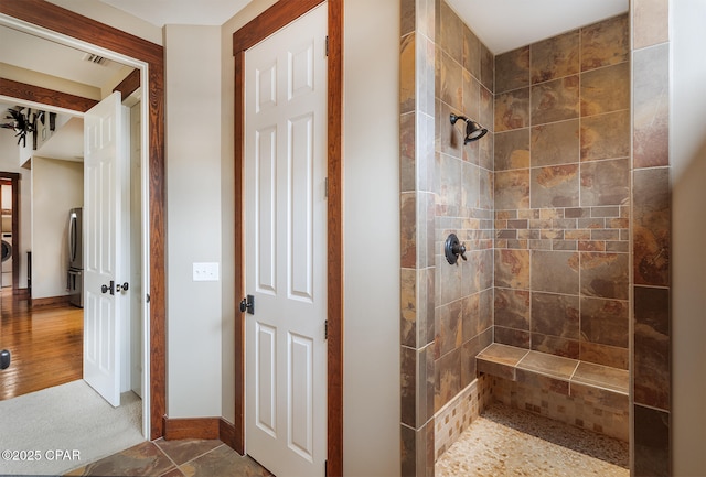 bathroom with baseboards and tiled shower