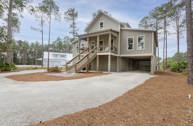 view of front of property with driveway, a carport, board and batten siding, a porch, and stairs