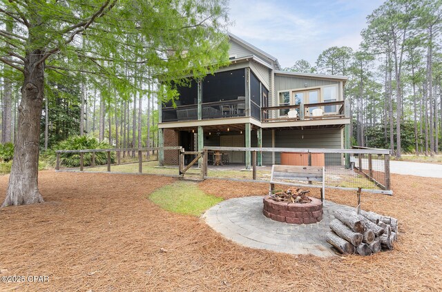 rear view of house featuring an outdoor fire pit, a deck, a sunroom, and a patio