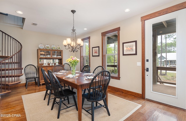 dining space featuring an inviting chandelier, visible vents, light wood-style floors, baseboards, and stairs