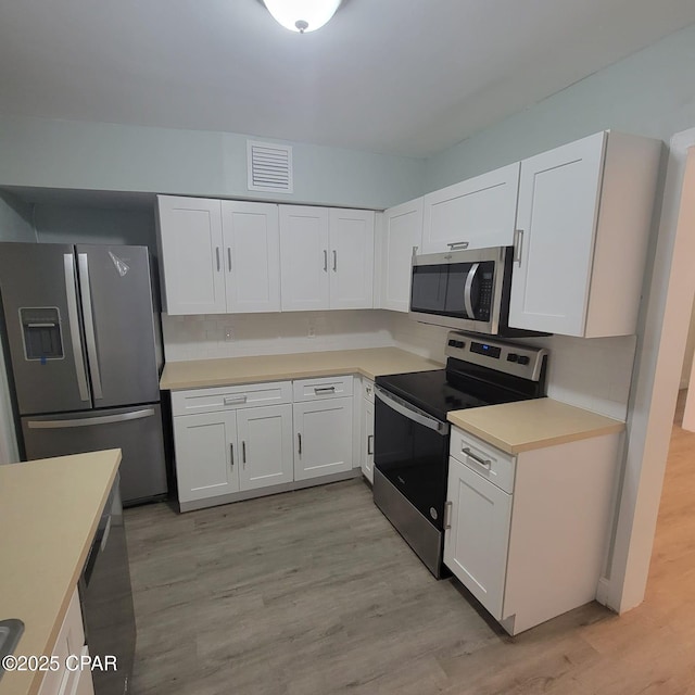 kitchen with white cabinets, light countertops, light wood-style floors, and appliances with stainless steel finishes