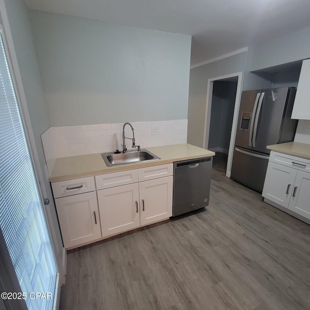 kitchen with decorative backsplash, appliances with stainless steel finishes, a sink, and light wood-style flooring