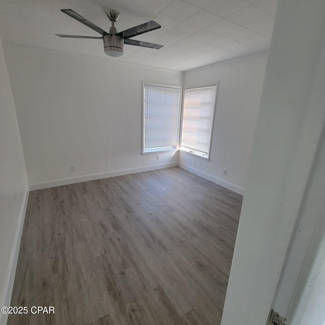spare room featuring baseboards, a ceiling fan, and wood finished floors