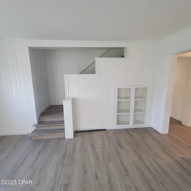 stairs featuring wood walls, baseboards, and wood finished floors