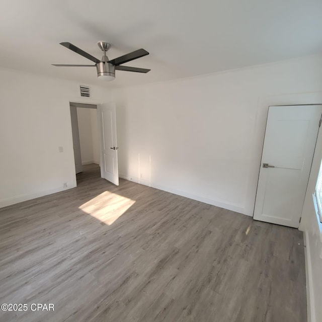 unfurnished room featuring ceiling fan, baseboards, wood finished floors, and visible vents