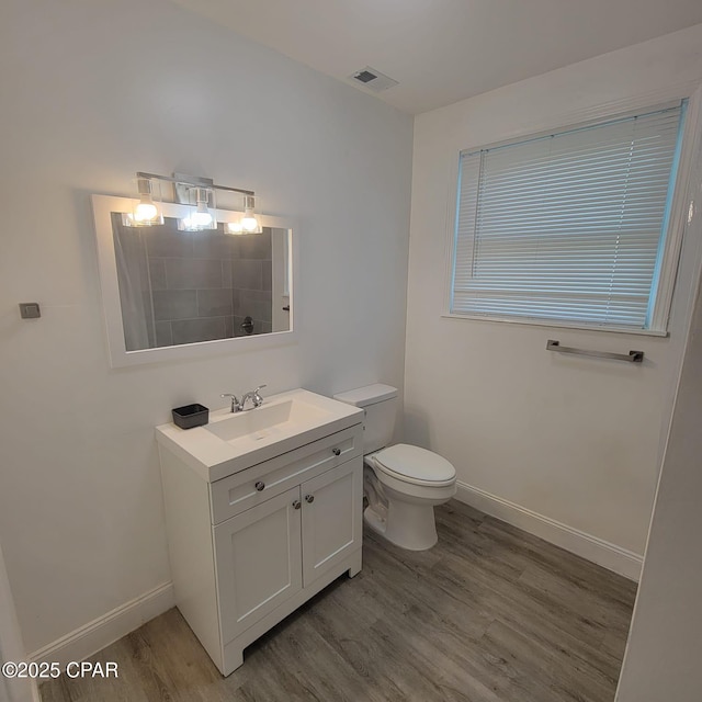 bathroom featuring toilet, baseboards, visible vents, wood finished floors, and vanity