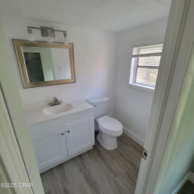 bathroom featuring toilet, vanity, wood finished floors, and baseboards