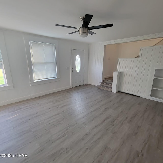 foyer entrance featuring stairway, baseboards, a healthy amount of sunlight, and wood finished floors