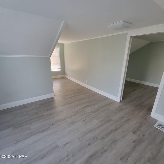 additional living space featuring lofted ceiling, baseboards, wood finished floors, and visible vents