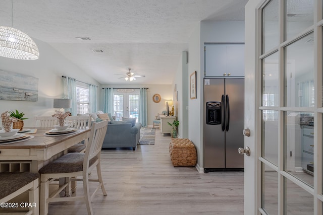 dining space with a ceiling fan, light wood-type flooring, lofted ceiling, and a textured ceiling