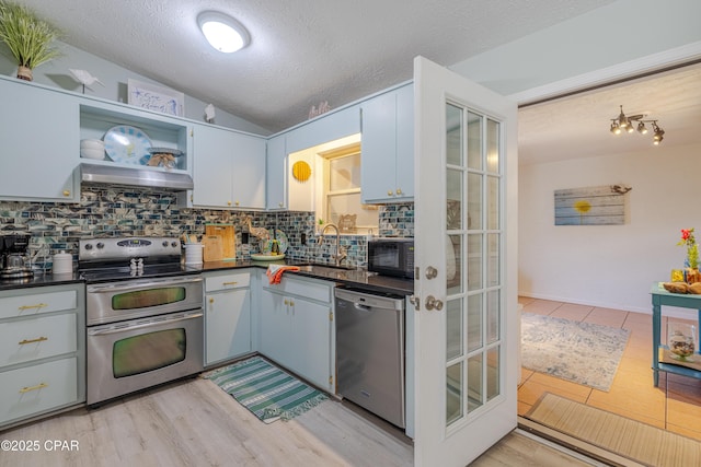 kitchen featuring tasteful backsplash, dark countertops, appliances with stainless steel finishes, a textured ceiling, and under cabinet range hood