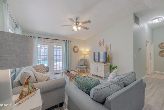 living room featuring baseboards, a ceiling fan, light wood-style floors, french doors, and lofted ceiling