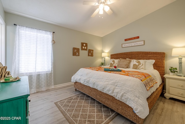 bedroom featuring ceiling fan, light wood finished floors, baseboards, and lofted ceiling