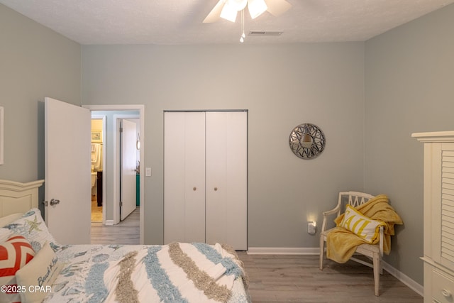 bedroom with ceiling fan, light wood-style flooring, a textured ceiling, a closet, and visible vents