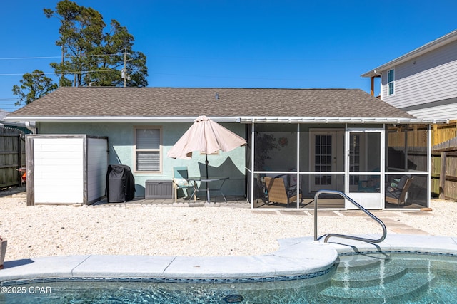 rear view of property featuring a fenced in pool, a patio area, roof with shingles, and fence