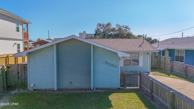 rear view of property featuring a yard, a fenced backyard, stucco siding, and a chimney
