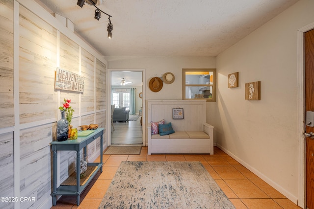 living area with track lighting, tile patterned floors, and baseboards