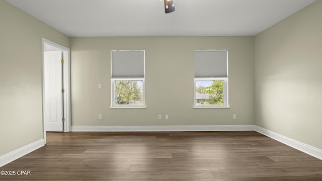 spare room with baseboards, ceiling fan, dark wood-style flooring, and plenty of natural light