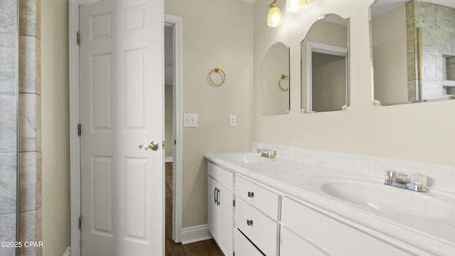 bathroom with baseboards, double vanity, and a sink