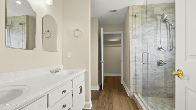bathroom featuring a shower stall, a sink, visible vents, wood finished floors, and a walk in closet