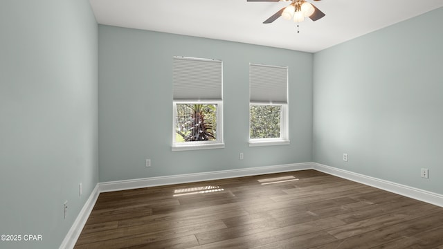 unfurnished room featuring dark wood-style flooring, ceiling fan, and baseboards